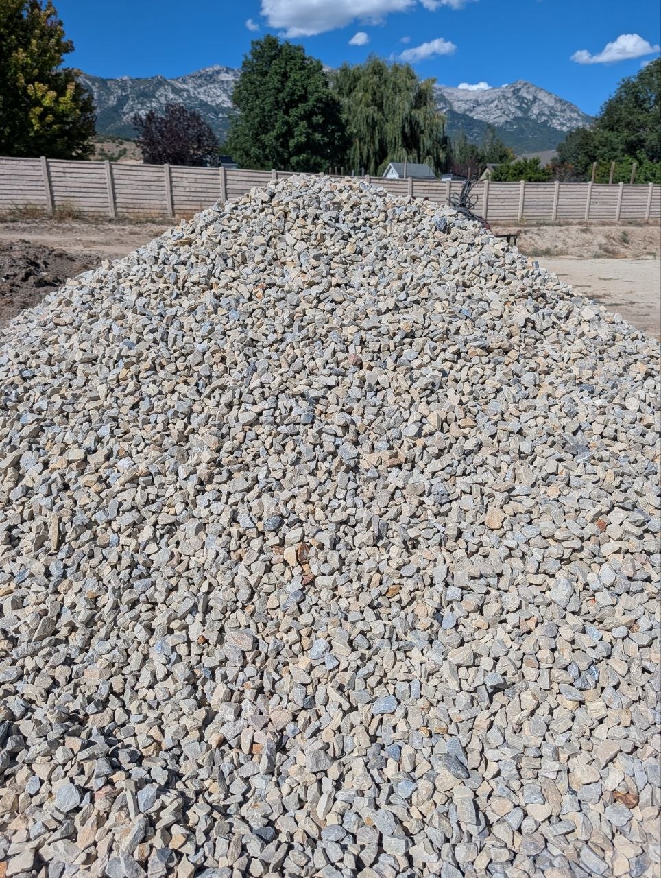 Large pile of angular 1.5″ gravel at an Alpine, Utah property with a mountain backdrop.
