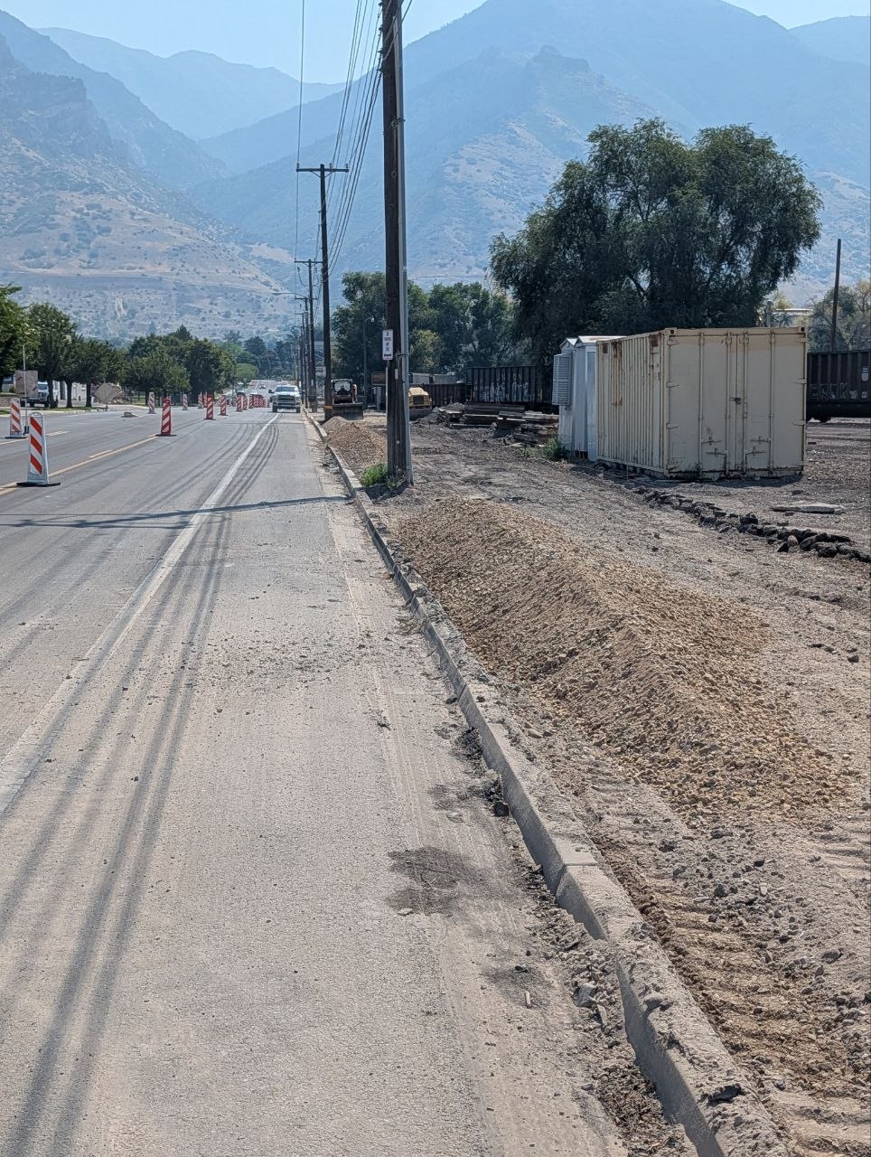 Road base placed by side dump into a sidewalk work area beside an active roadway