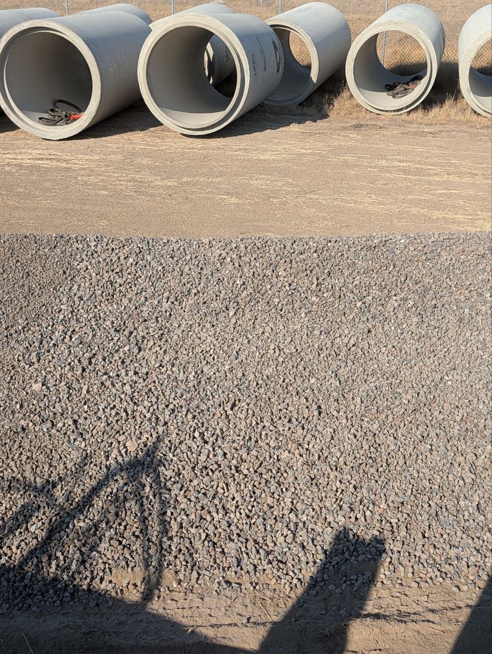 3/4 gravel placed at a West Jordan construction site beside staged precast concrete drainage pipe.